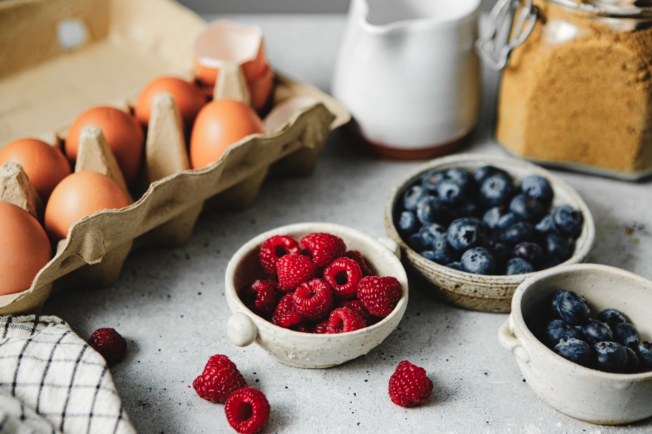 Breakfast ingredients with eggs and berries on a kitchen table