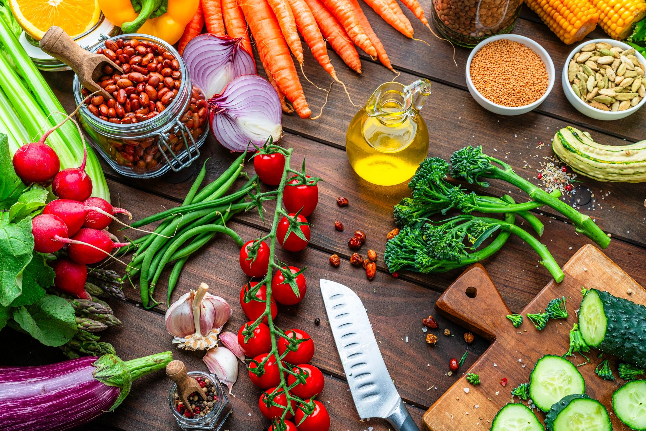 Fresh garden vegetables and pantry ingredients arranged on a kitchen table