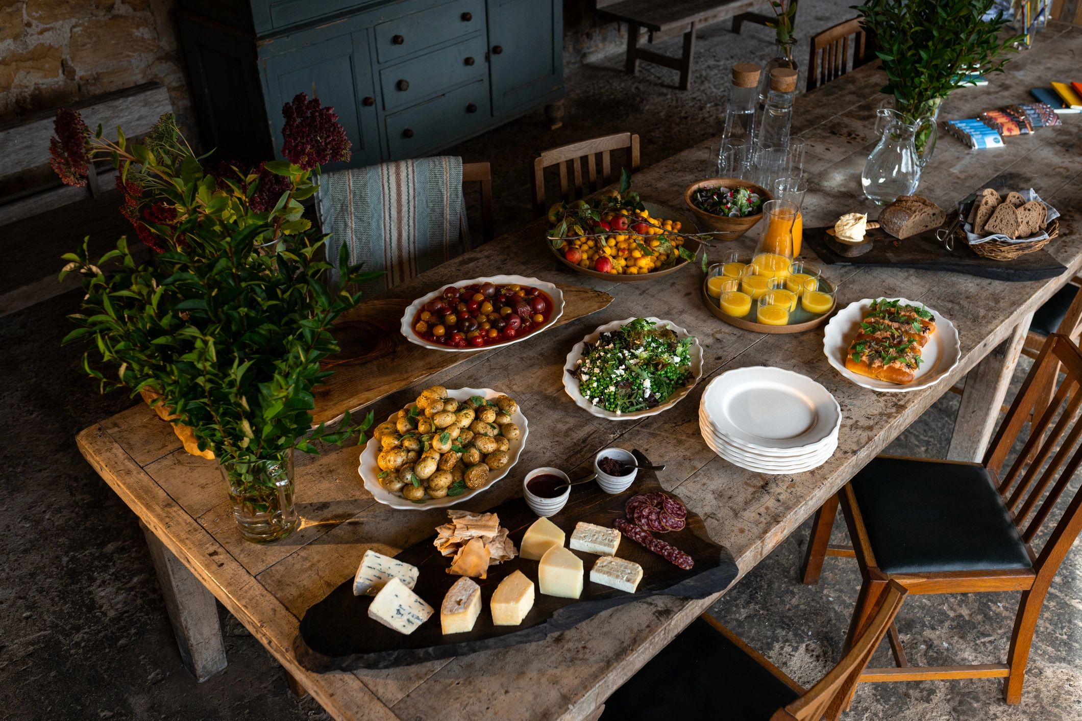 A generous shared table of fresh food in a countryside setting