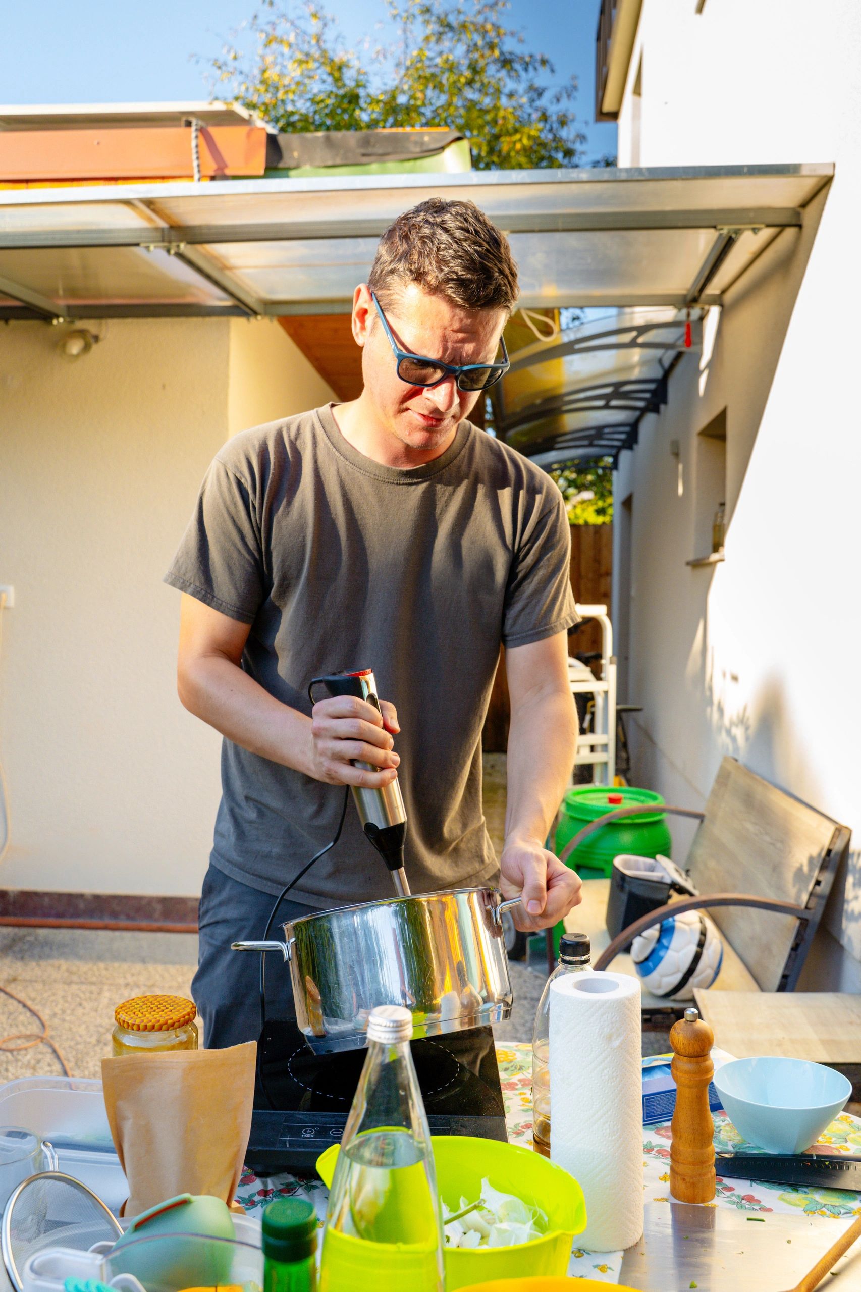 Cook preparing vegetables at a sunlit outdoor kitchen table